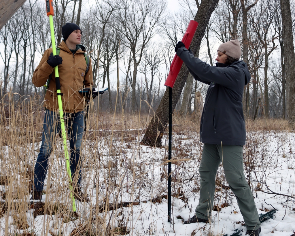 The author installs a metal post to mark the center of a sample plot. Restoration Ecologist Dan Sandacz holds a Bad Elf to calibrate GPS coordinates. Photo © Lake County Forest Preserves.